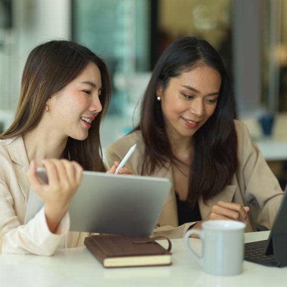 Two businesswomen talking to each other while working in office room